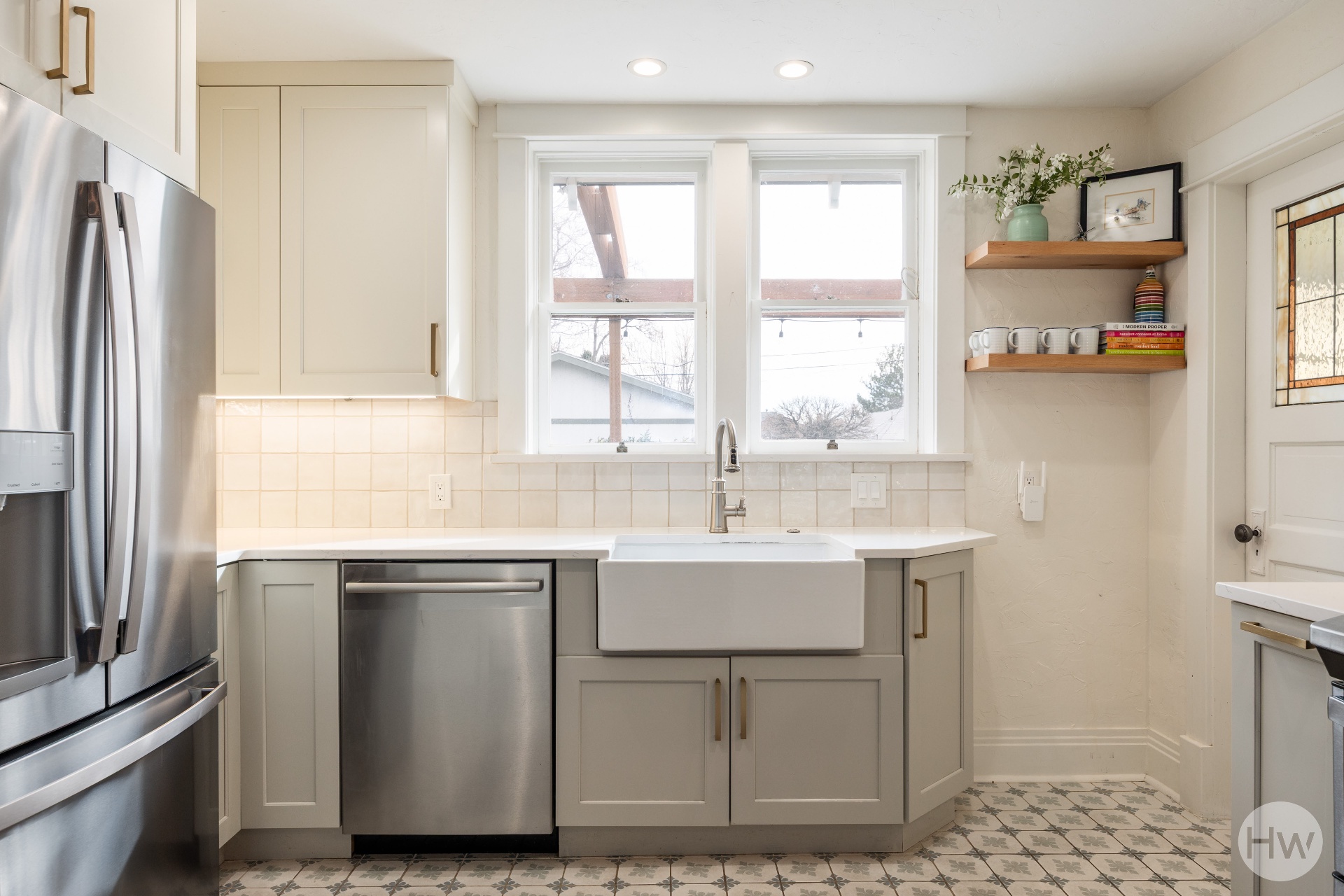 Light-filled kitchen with a white farmhouse sink, soft gray cabinetry, and patterned tile floor